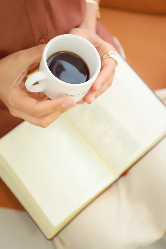 Mãos servindo uma xícara de café sobre um caderno aberto